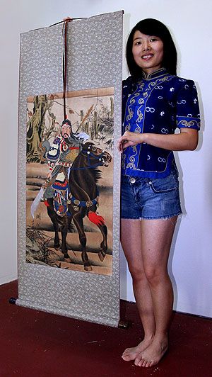 Sandy holding a Guan Gong wall scroll